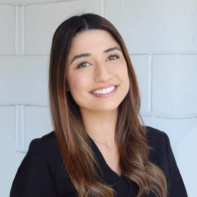 Smiling woman with long hair, wearing a black top, representing confidence and satisfaction.