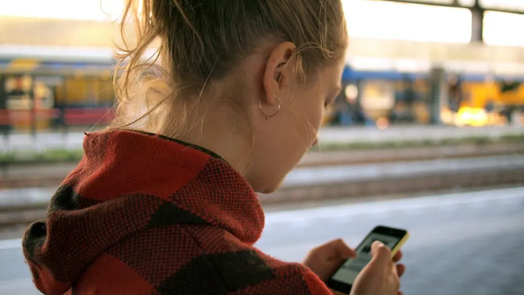 Person at train station using smartphone.