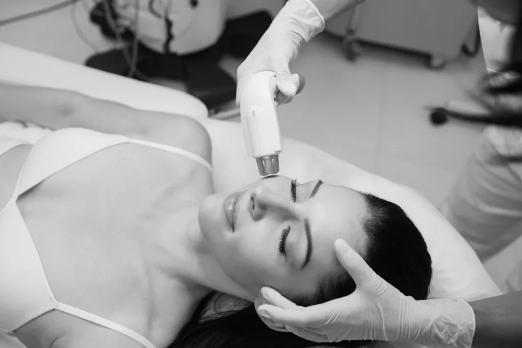 Woman receiving facial laser treatment at a plastic surgery center.