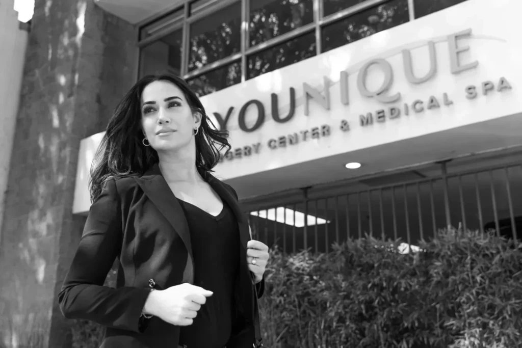Woman in black suit in front of a plastic surgery center entrance.
