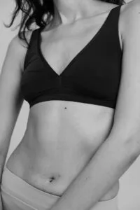 Woman in black bra showcasing smooth abdominal contour.