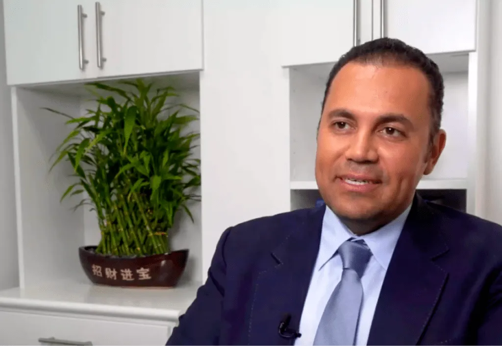 Smiling professional in a suit at a plastic surgery center office.