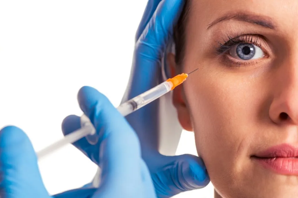 Close-up of a cosmetic injection near a patient's eye at a plastic surgery center.