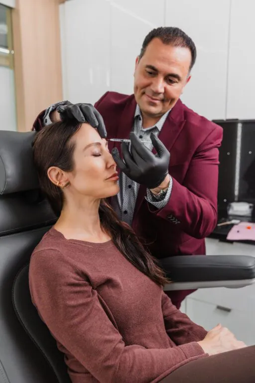 Doctor administering botox injection to a woman's forehead at a plastic surgery center.