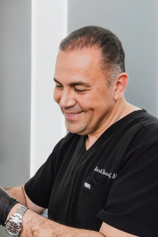 Smiling plastic surgeon in scrubs at a clinic.