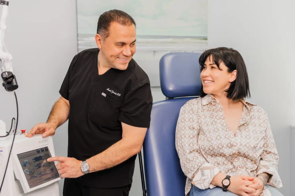 Plastic surgeon consulting with a smiling patient in a medical office.