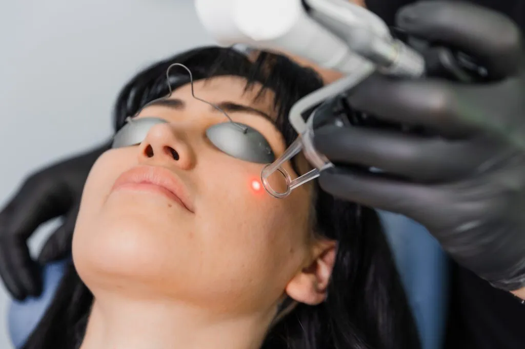 Woman receiving laser facial treatment at plastic surgery center.