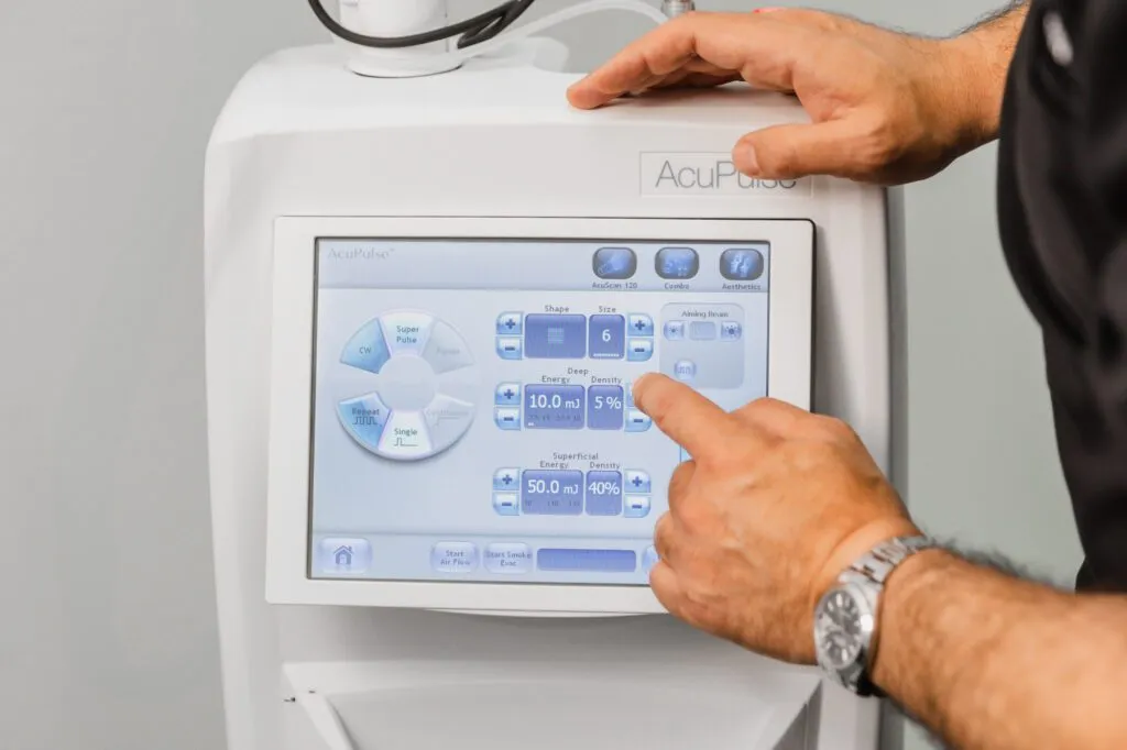 Person adjusting settings on a plastic surgery laser device touchscreen.