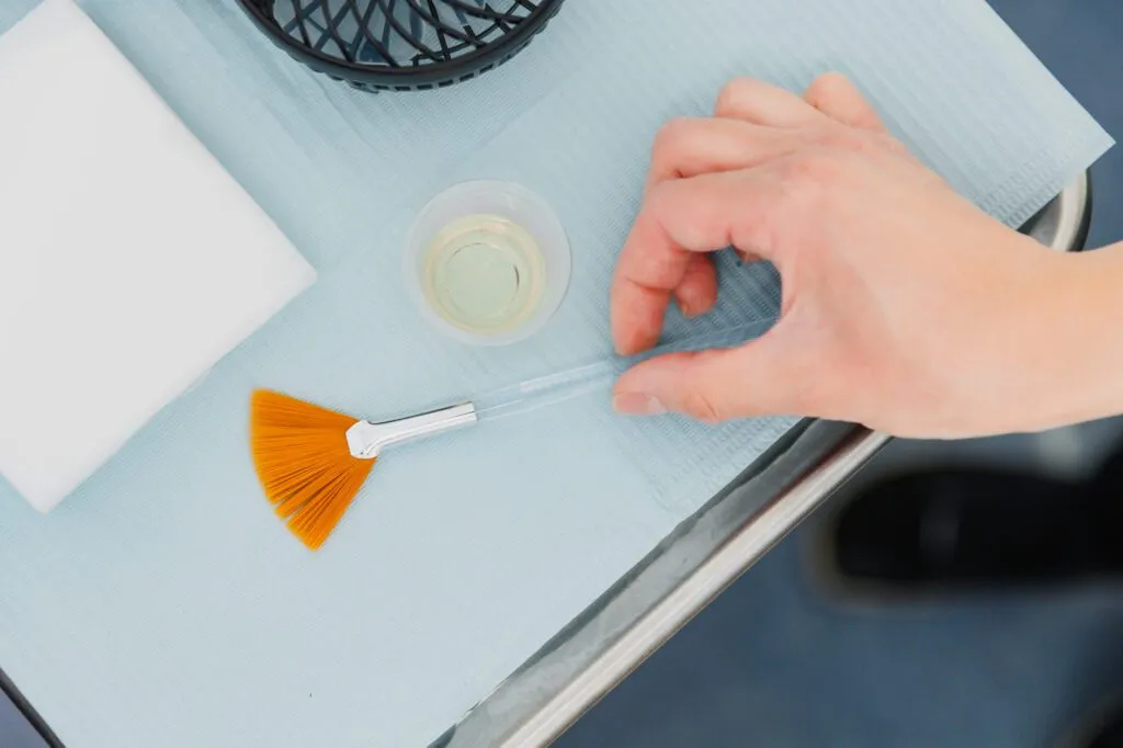 Hand preparing skincare brush for cosmetic treatment at a plastic surgery center.