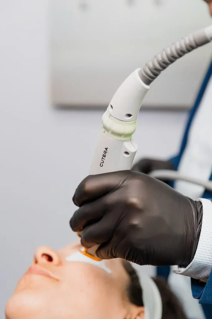 Close-up of a professional performing non-invasive laser skin treatment at a plastic surgery center.