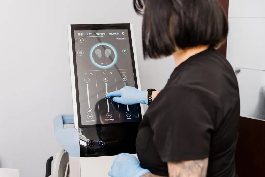 Technician using a touchscreen device at a plastic surgery center.