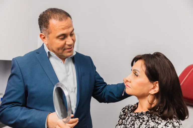 Plastic surgeon consulting with a patient, holding a mirror.