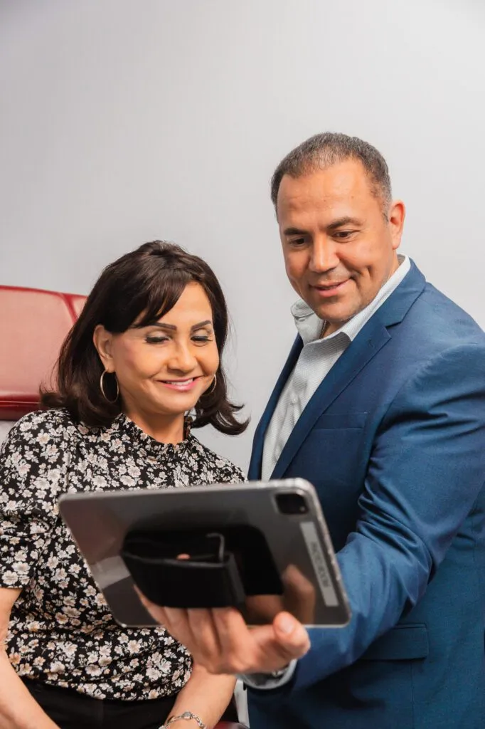 Plastic surgeon consulting with a patient while reviewing images on a tablet.