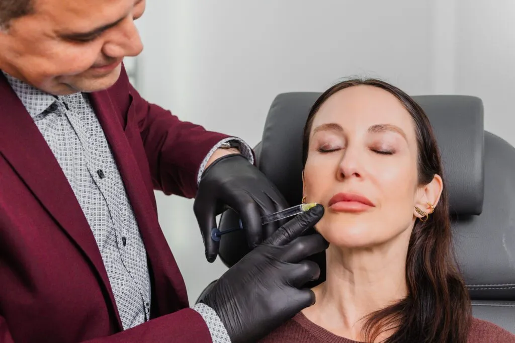 Doctor performing dermal filler injection at a plastic surgery center.