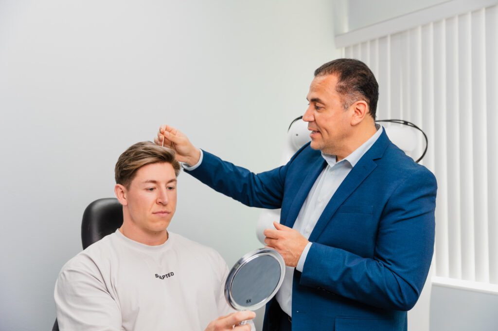 Plastic surgeon consulting male patient with mirror.