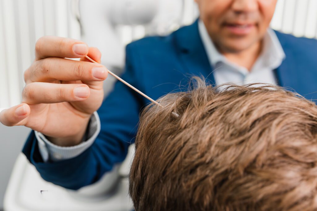 Doctor performing hair transplant procedure at a plastic surgery center.