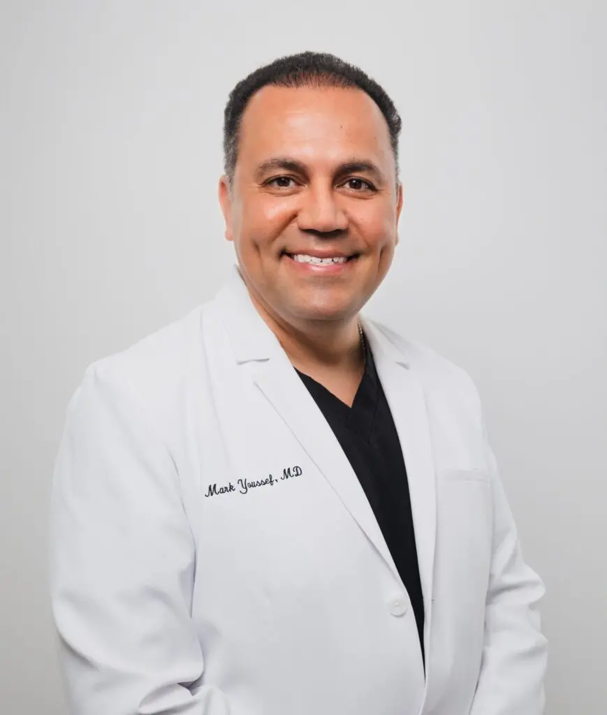Smiling plastic surgeon in a white coat at a medical center.