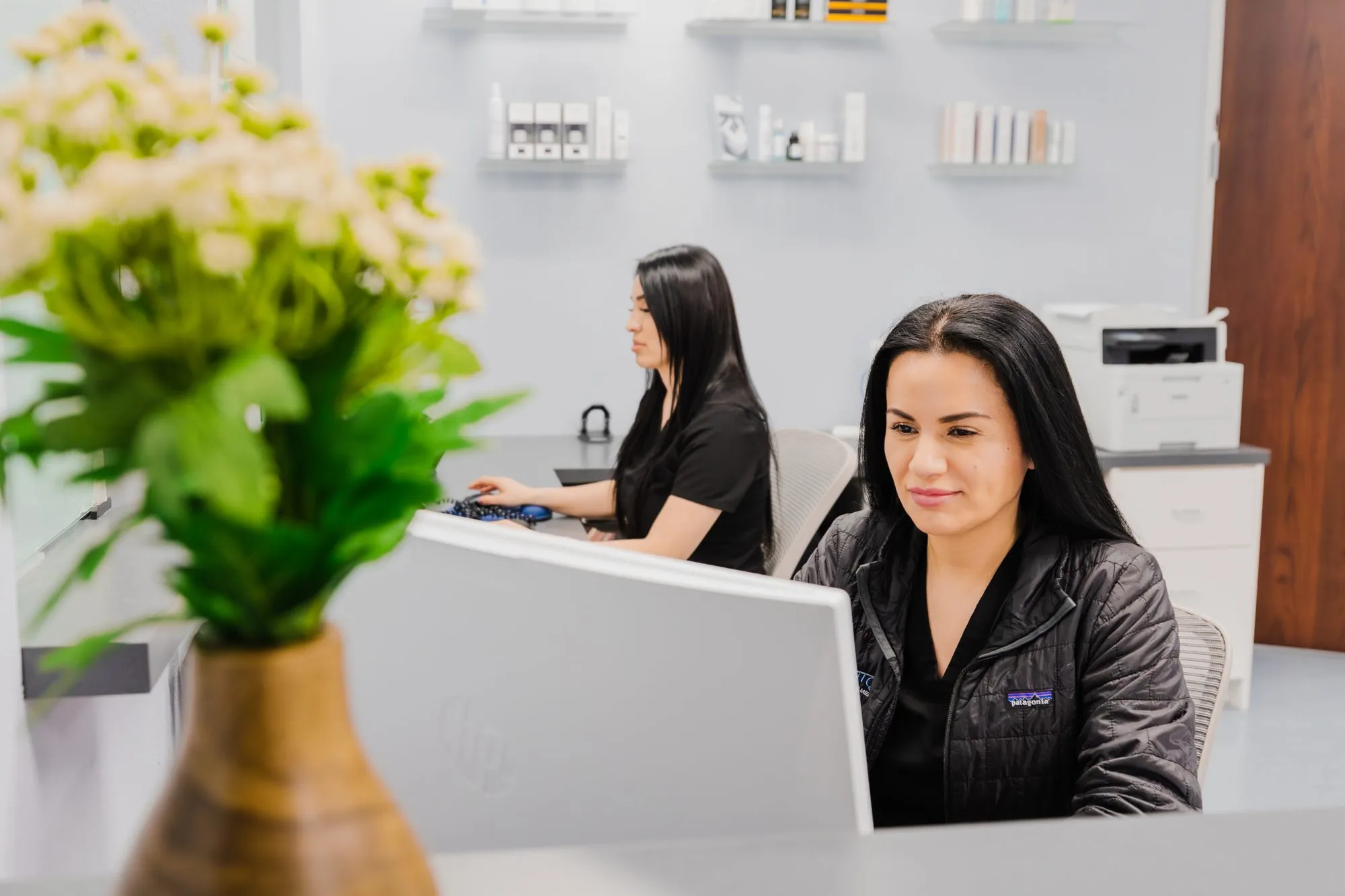 Receptionists working at a plastic surgery center front desk.