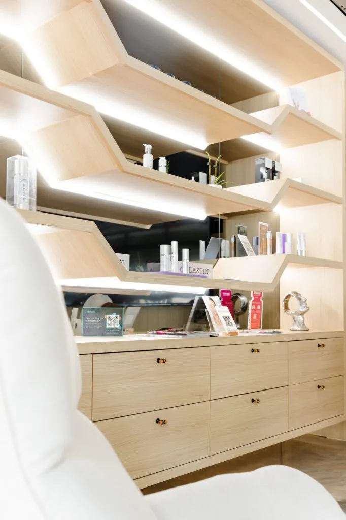 Modern plastic surgery center interior with wooden shelves displaying skincare products.