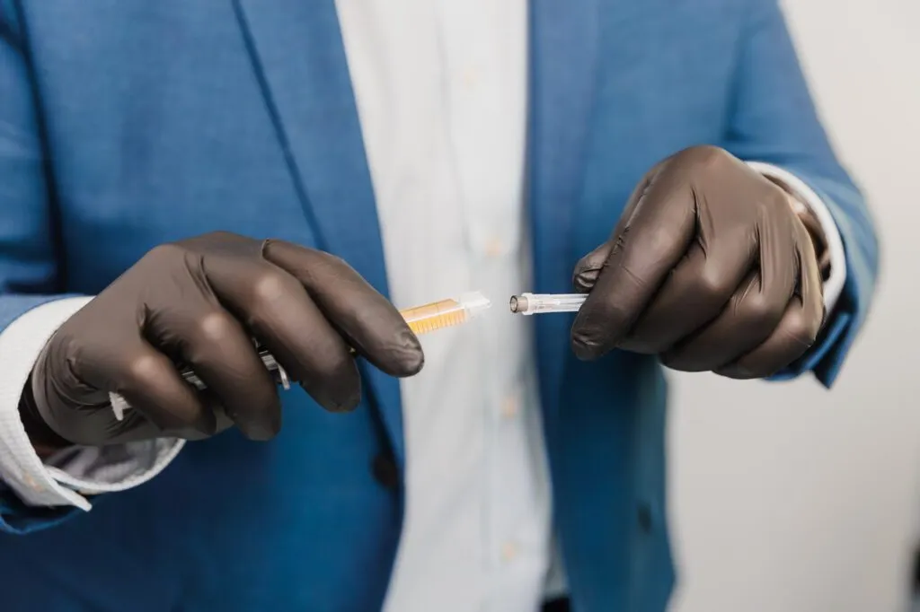 Doctor in blue suit preparing an injectable syringe with gloves.