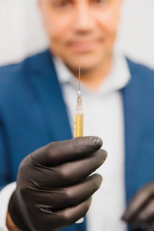 Doctor holding syringe in gloved hand at a plastic surgery center.