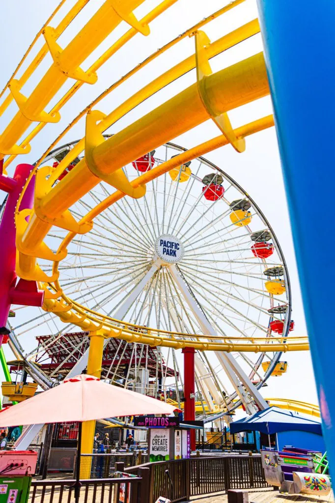 Bright and colorful amusement park with Ferris wheel and roller coaster under a clear sky.