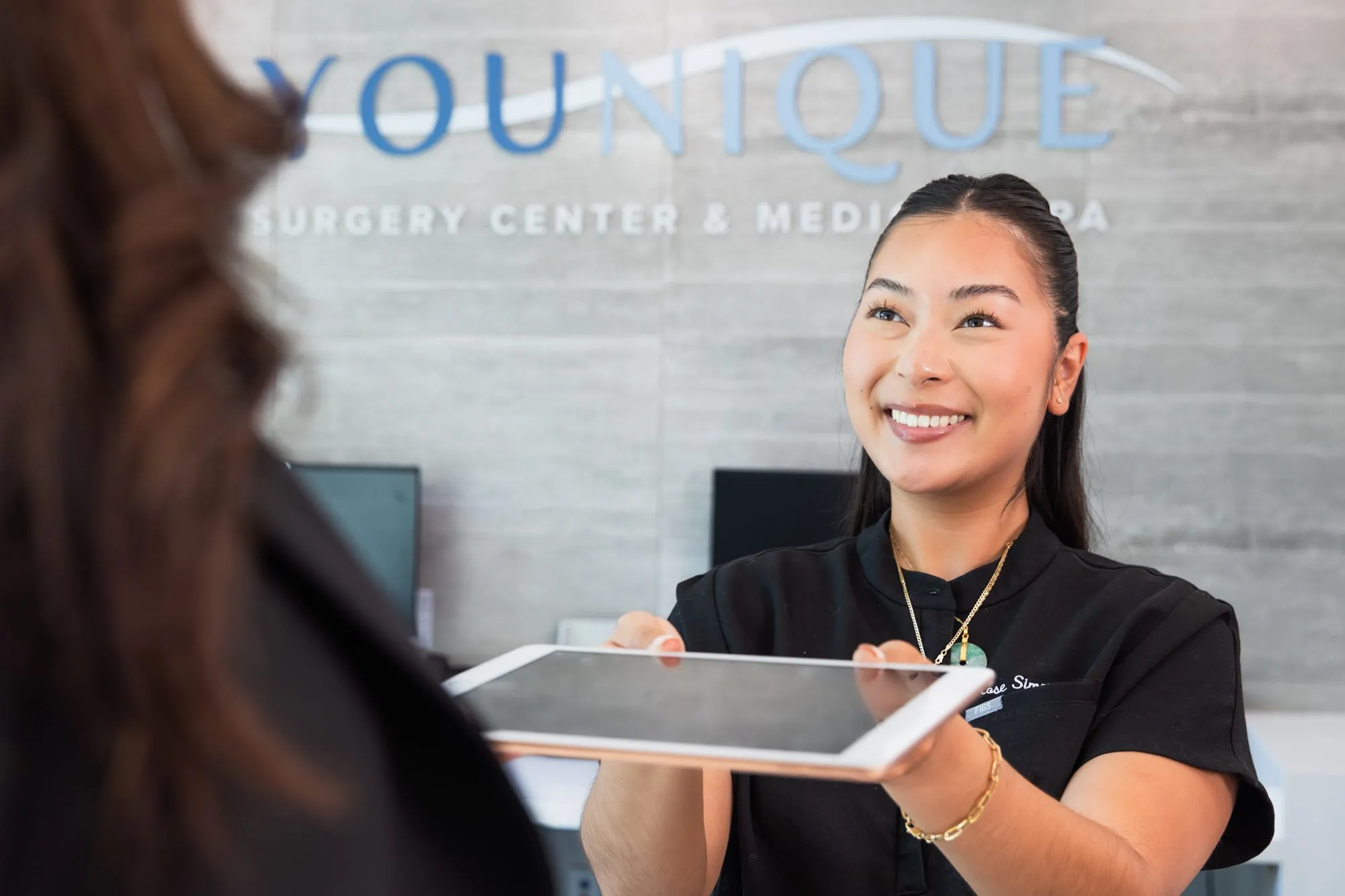 Smiling receptionist at a Medspa in Oxnard, near Santa Monica holding a tablet.