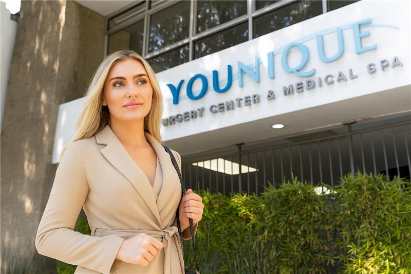 Woman standing confidently in front of a plastic surgery center building.