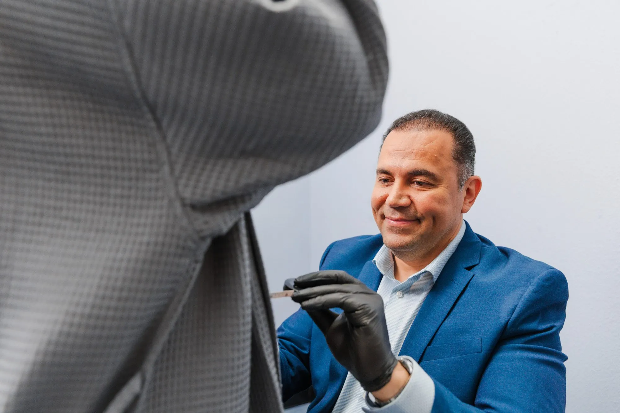 Plastic surgeon in blue suit preparing for a procedure with a patient.