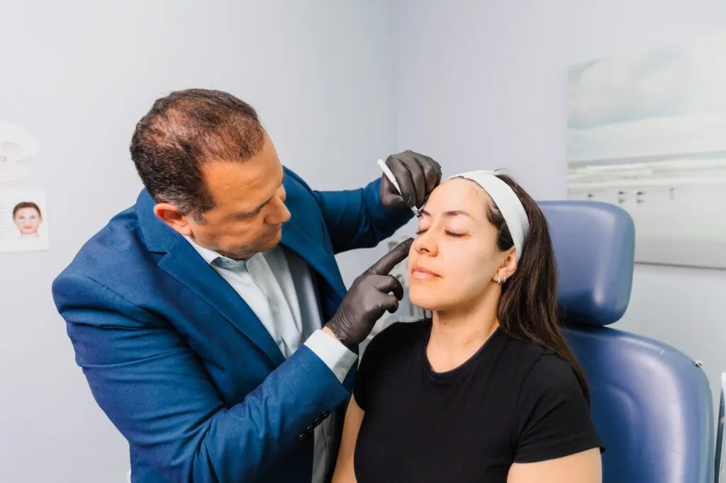 Plastic surgeon performing a consultation with a patient in a clinical setting.