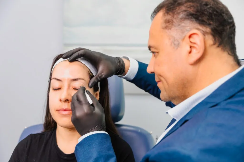 Doctor performing a facial procedure on a patient at a plastic surgery center.